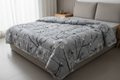 Royce Grey Blossom Comforter draped on a bed in a modern bedroom