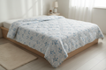 Royce Blue Leaf Comforter draped on a bed in a fresh modern bedroom